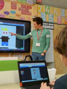Ali Maggs leads a coding workshop in a school, showing how to create pixel art characters